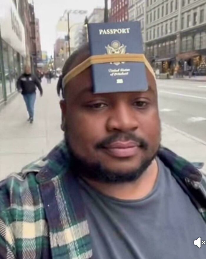 A man with two unhinged images of passports strapped to his forehead with a rubber band.