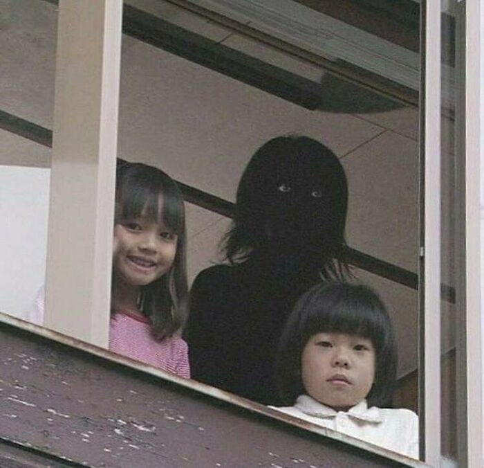 Two children with a dark, shadowy figure in the background, making it an unhinged image.