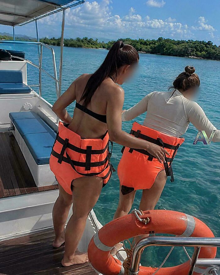 Two women wearing life jackets incorrectly on a boat, creating an unhinged image.