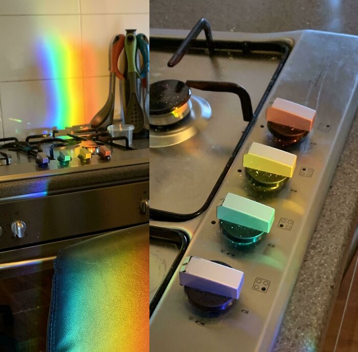 A rainbow light ray perfectly synced and falling across a kitchen stovetop and its knobs.