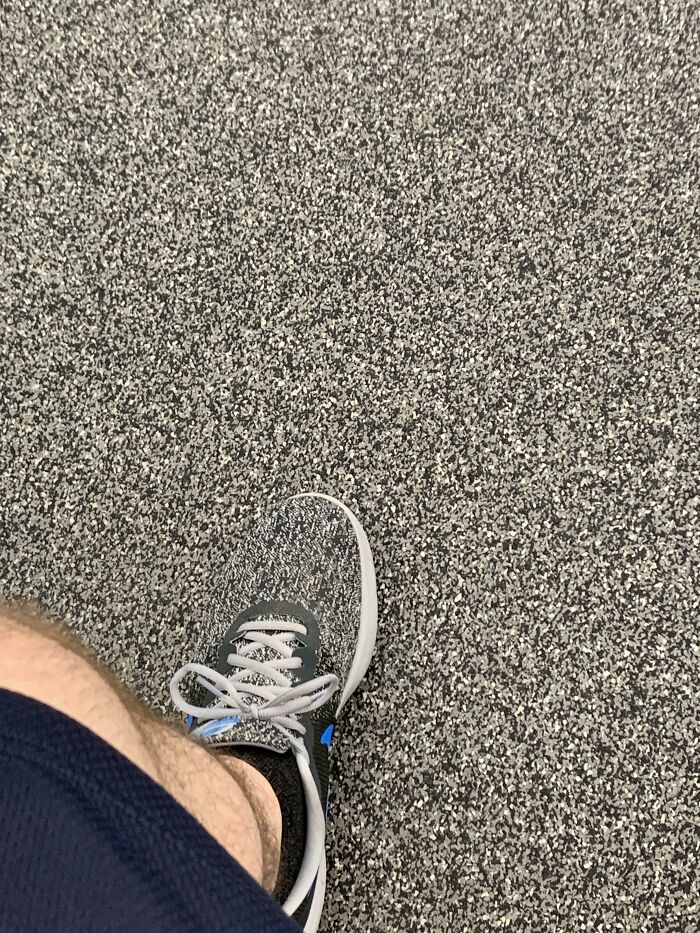 A foot wearing a sneaker that perfectly syncs with the pattern of the speckled floor, an amazing example of something synced just right.