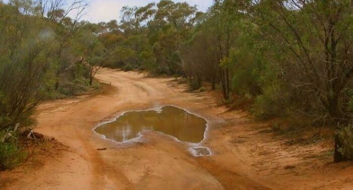 A puddle on a dirt road perfectly synced to the shape of Australia, an amazing example of something synced just right.