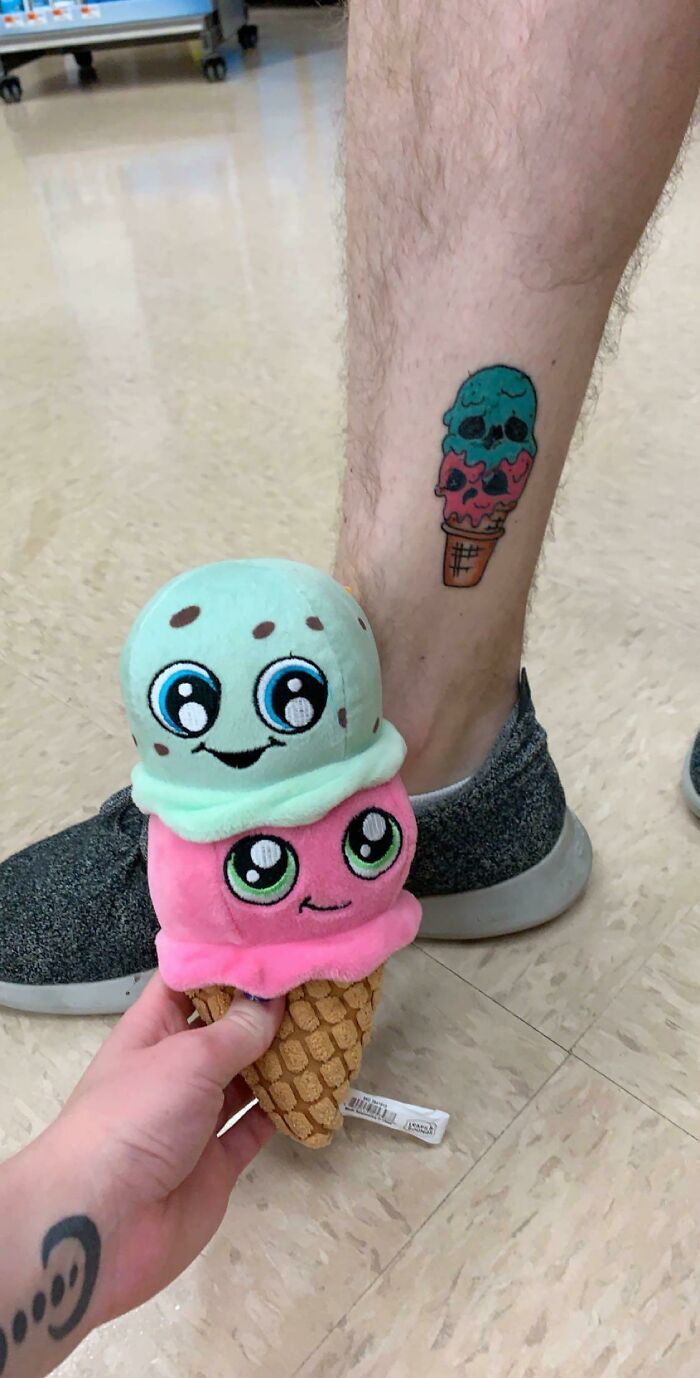 A person holding a plush ice cream toy next to a leg with an ice cream cone tattoo, a moment synced just right.