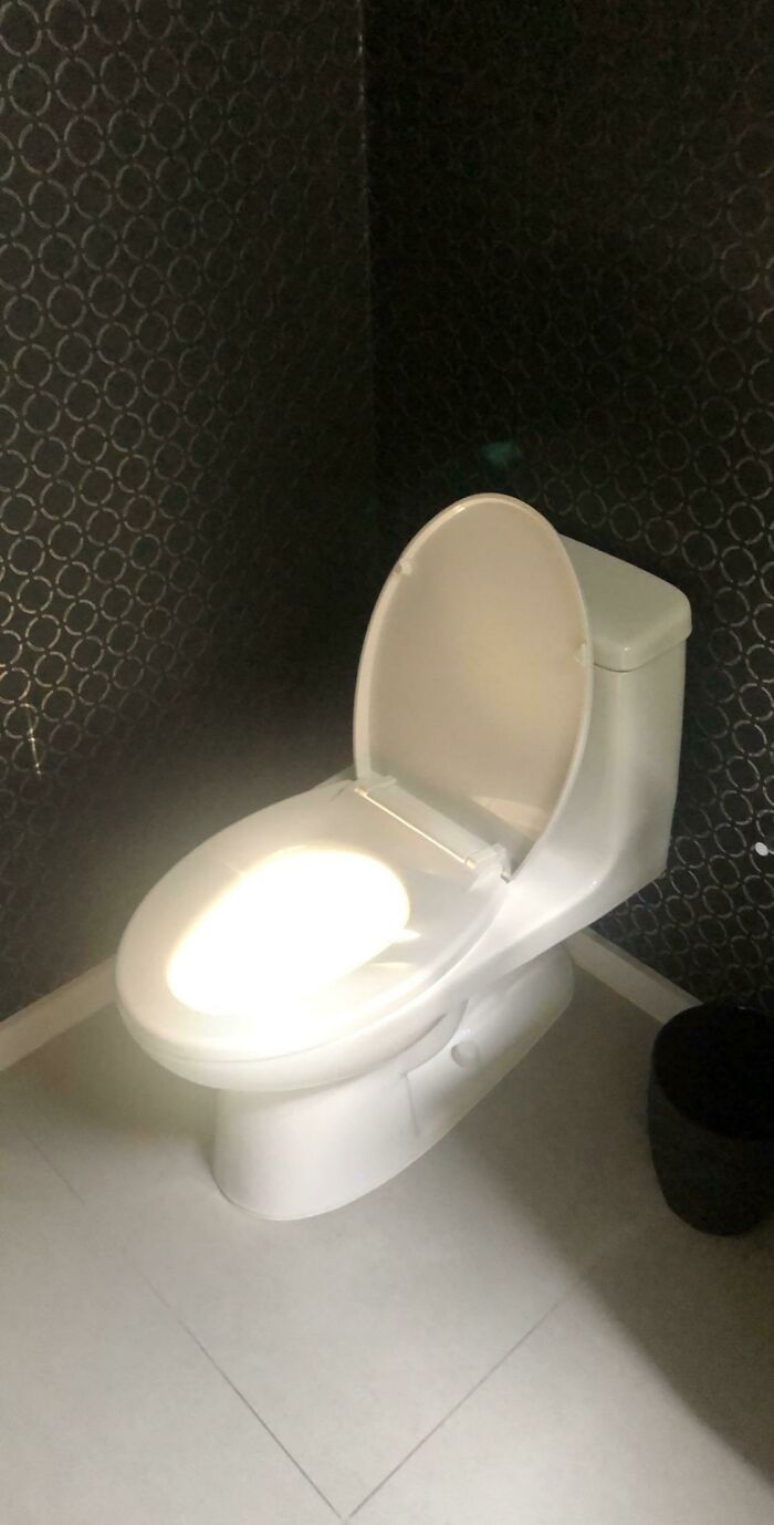 A toilet with a bright light synced perfectly on its seat and lid, creating an amazing glowing effect.