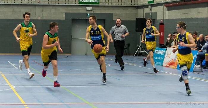 Basketball players and referee run down the court, perfectly synced, an amazing time.