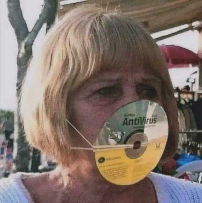 An unhinged image of a woman wearing an old Norton AntiVirus CD as a makeshift face mask, held by elastic bands.