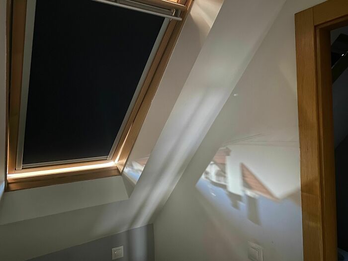 Sunlight shining through a skylight, projecting a perfect image of a house roof on the wall, showing something synced just right.