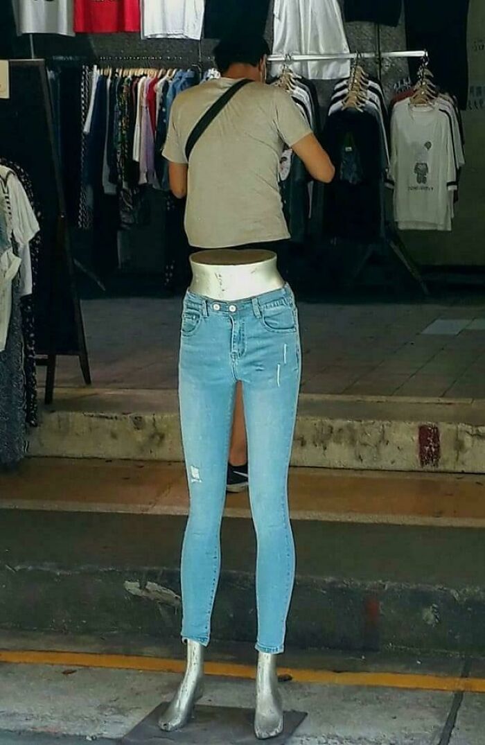An unhinged image of a headless mannequin wearing light blue jeans, creating a bizarre sight in a store.