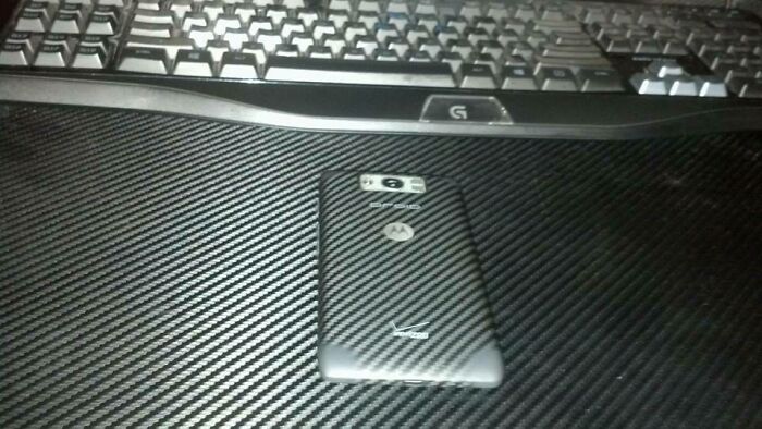 A Motorola phone with a carbon fiber skin, perfectly synced with a carbon fiber desk pad and keyboard.