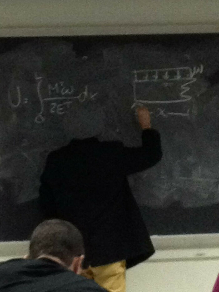 A headless figure writing a complex formula on a blackboard, creating a perfectly synced, amazing illusion.