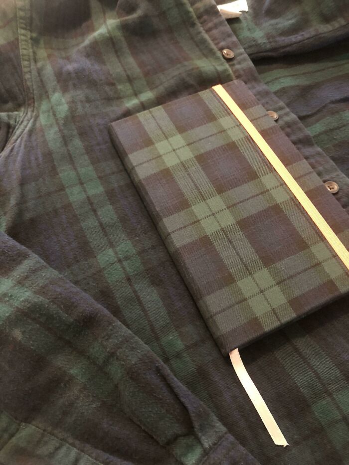 A plaid notebook perfectly synced with a plaid shirt, showcasing amazing visual harmony.