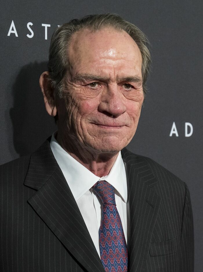 Close-up of Tommy Lee Jones looking directly at the camera, highlighting his bio and career highlights.