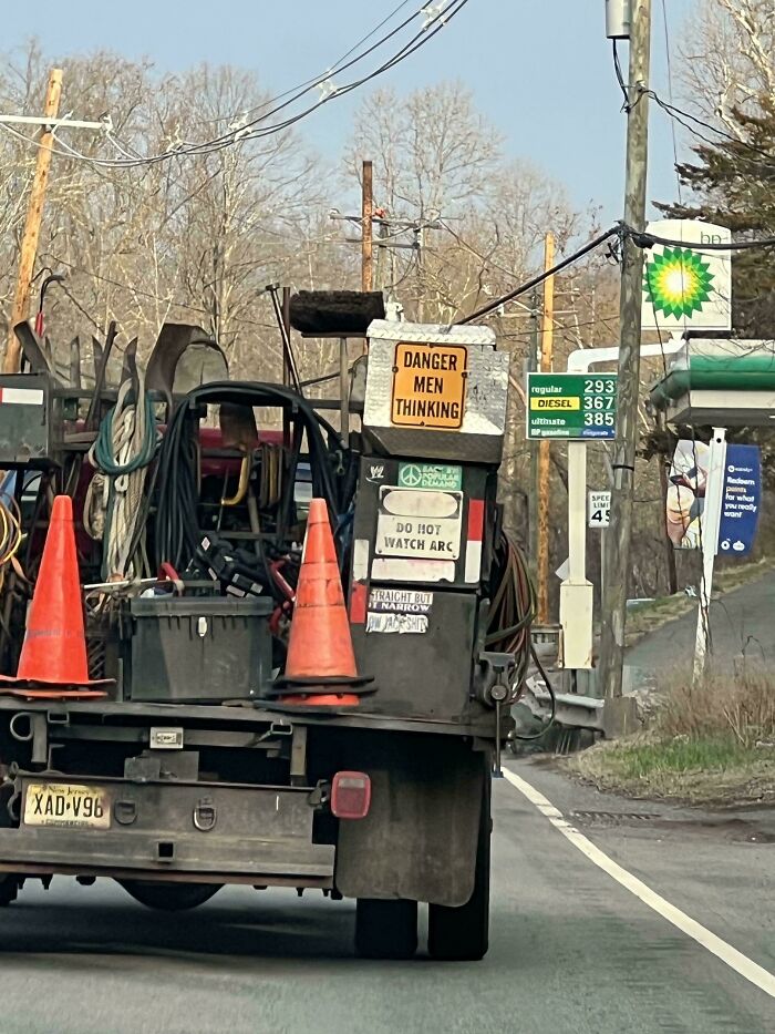 A chaotic sign spotted in the wild on the back of a utility truck, reading Danger Men Thinking.