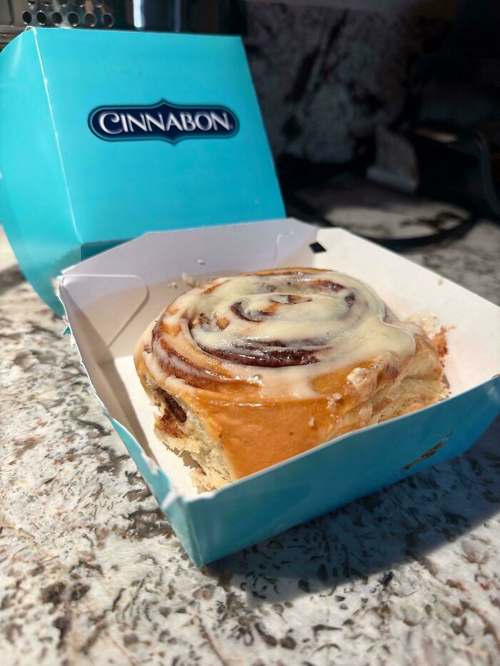 A Cinnabon cinnamon roll in a light blue box, illustrating products and services getting worse and more expensive.