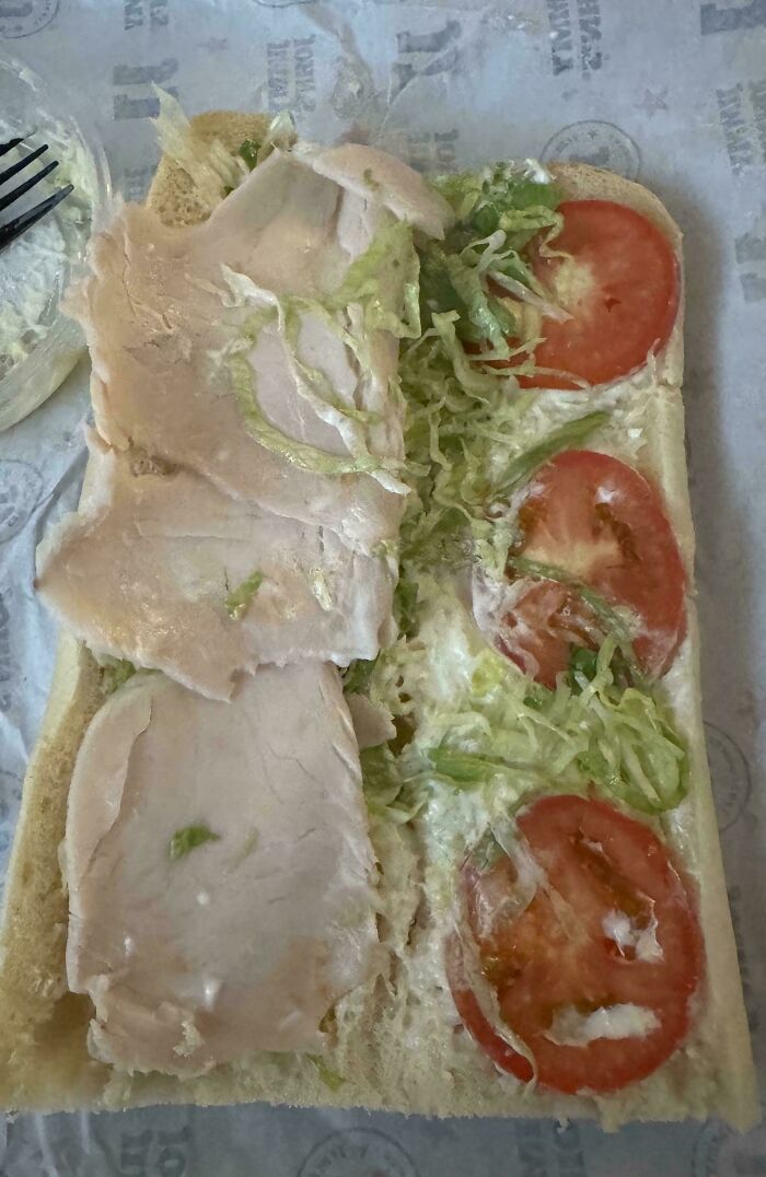 An unappetizing turkey sandwich on a piece of paper, representing products getting worse while more expensive.