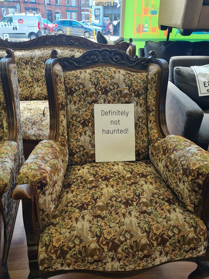 A chaotic sign on an armchair in a shop that reads, Definitely not haunted!, making people question reality.