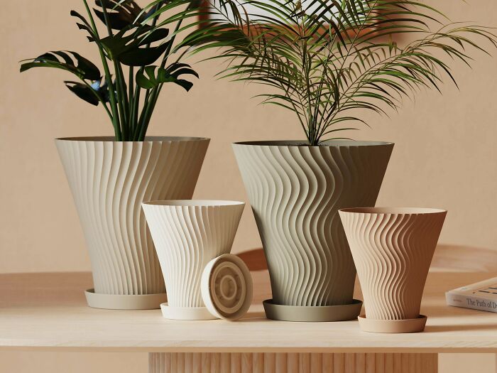 Various sizes of elegantly designed plant pots with wavy textures, showcasing items people 3D printed.