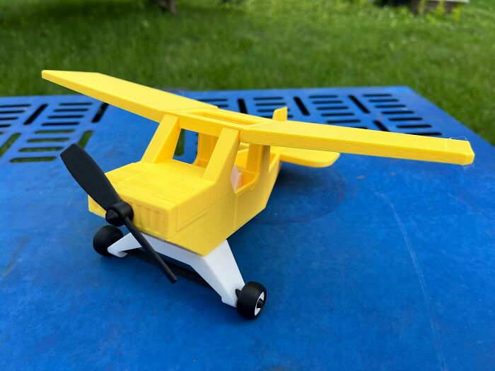 A vibrant yellow model airplane with a black propeller, a perfect example of something people needed and 3D printed.