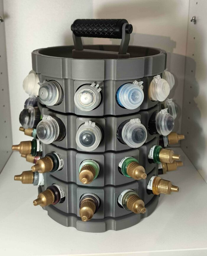 A multi-tiered gray rotating holder filled with various paint bottles, showcasing items people needed and 3D printed.