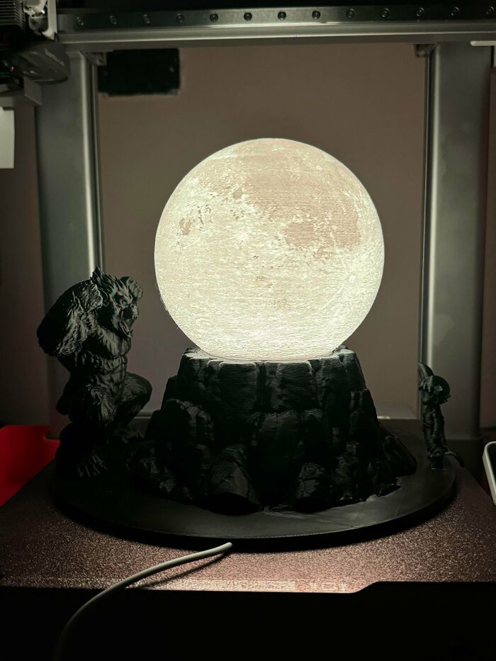 A glowing moon lamp with sculpted figures, an example of items made with 3D printers.