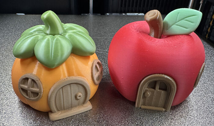 Two charming miniature houses, one shaped like a pumpkin and the other an apple, custom 3D printed for creative decor.