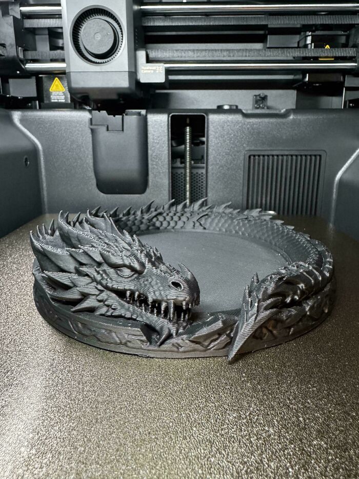 A detailed 3D printed dragon model inside a modern 3D printer, showcasing printing capabilities.