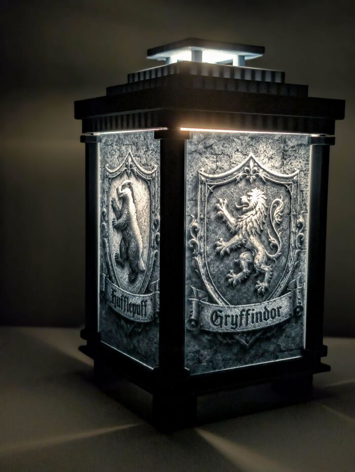 A glowing 3D printed lantern featuring detailed crests for Hufflepuff and Gryffindor houses.