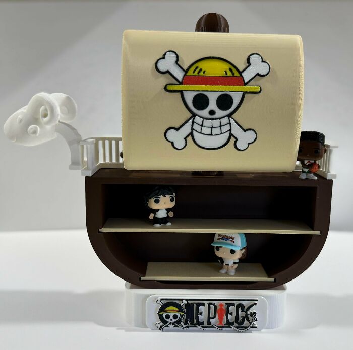 A 3D printed display shelf shaped like a pirate ship, featuring small figurines, highlighting custom items from 3D printers.