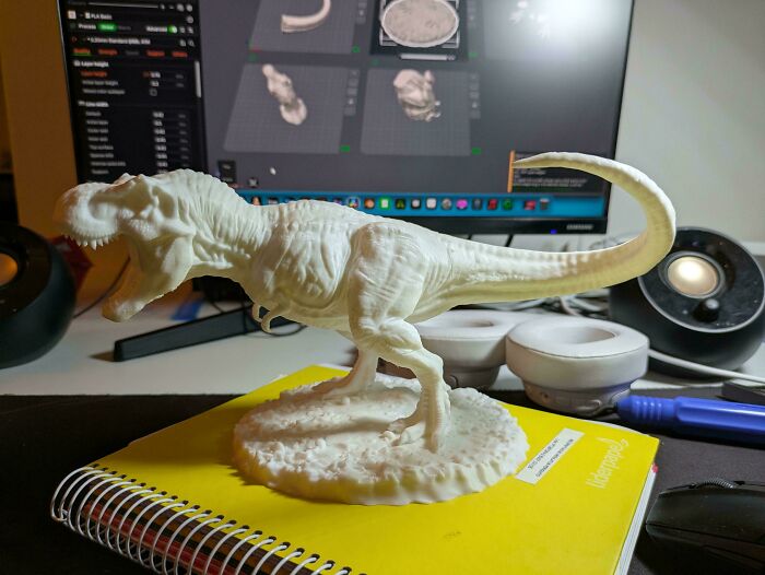 A detailed 3D printed T-Rex model on a yellow notebook, demonstrating the capabilities of 3D printers.