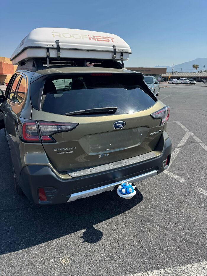 A Subaru Outback with a Roofnest rooftop tent and a 3D printed blue Koopa Shell hitch cover.