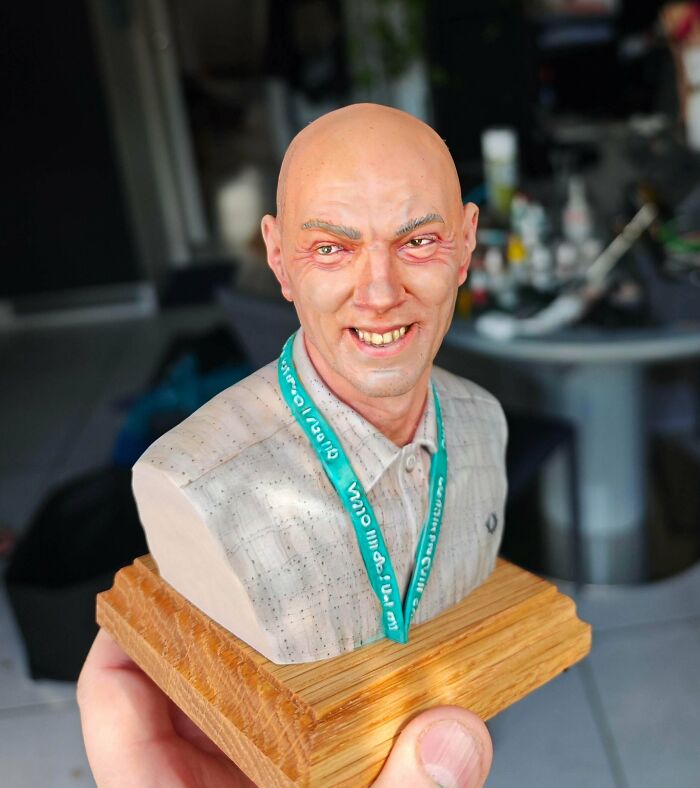 A highly realistic 3D printed bust of a smiling bald man wearing a patterned shirt and a lanyard.