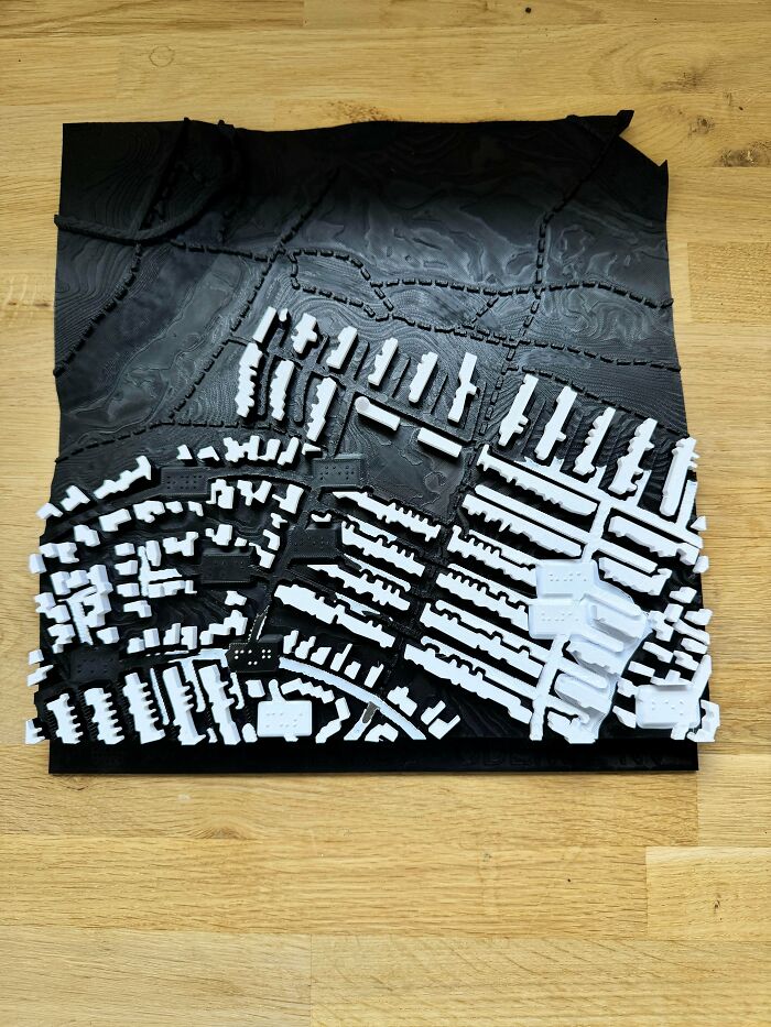 A detailed black and white 3D printed topographical map of a city, illustrating something people printed for a specific need.