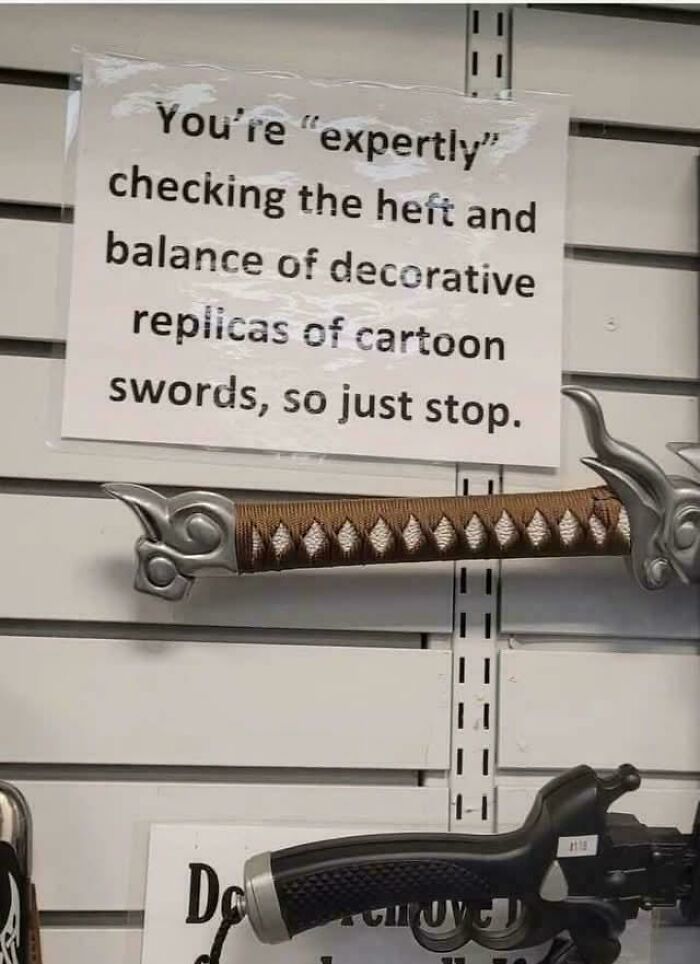 A chaotic sign spotted in the wild warning against expertly checking the heft and balance of decorative sword replicas.
