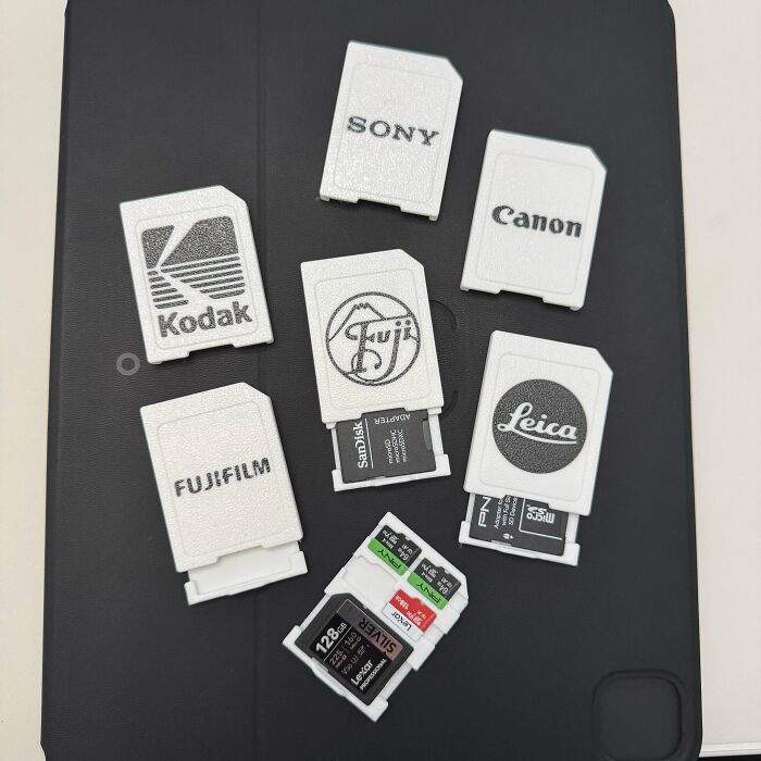 A collection of custom 3D printed SD card adapters for various camera brands, showcasing how people print what they need.