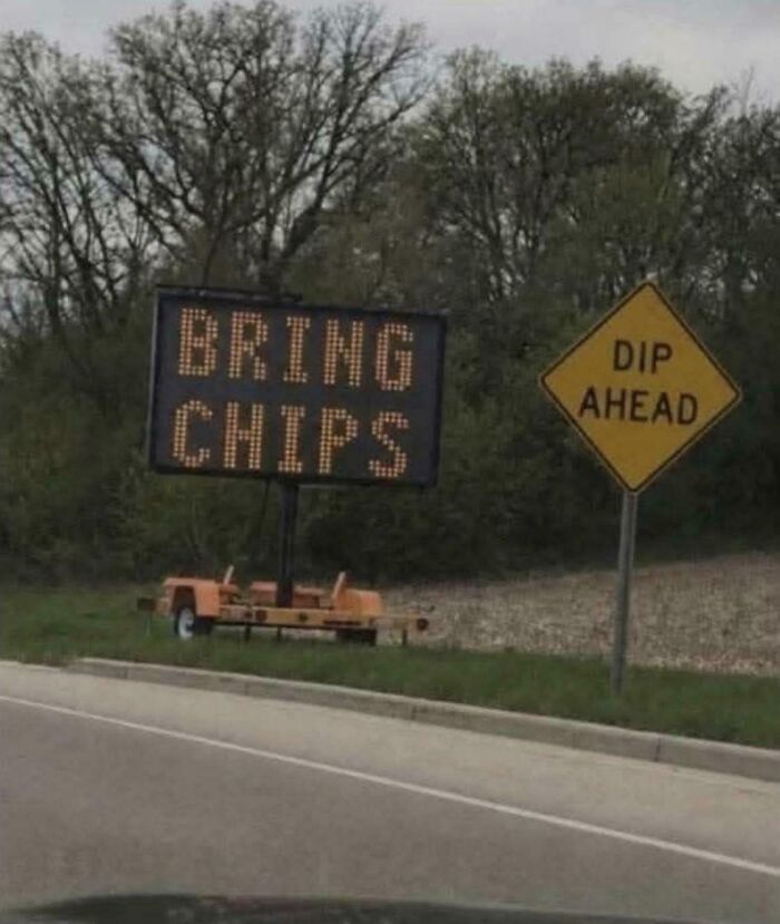 Two chaotic signs in the wild: an electronic road sign says BRING CHIPS, next to a yellow diamond DIPP AHEAD sign.