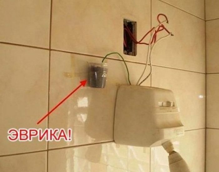 A DIY fail showing exposed wires connected to a hairdryer and a small cup on a tiled wall.