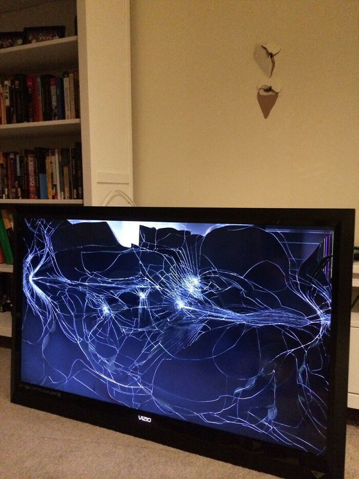 A DIY fail featuring a television with a completely shattered screen and a damaged wall, indicating an accident.