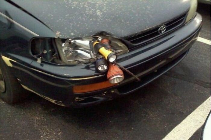 A car with flashlights taped to its front bumper, a DIY fail to replace a broken headlight.
