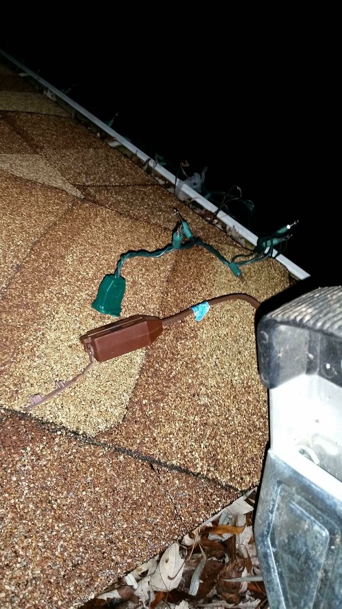 Unsafely wired holiday lights on a roof, demonstrating DIY fails.