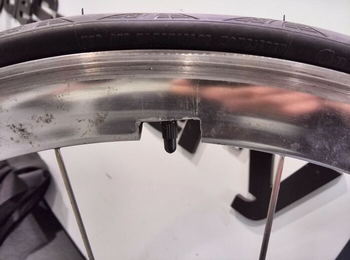 A close-up of a bicycle wheel showing a tire valve sticking out of a damaged rim, a DIY fail.