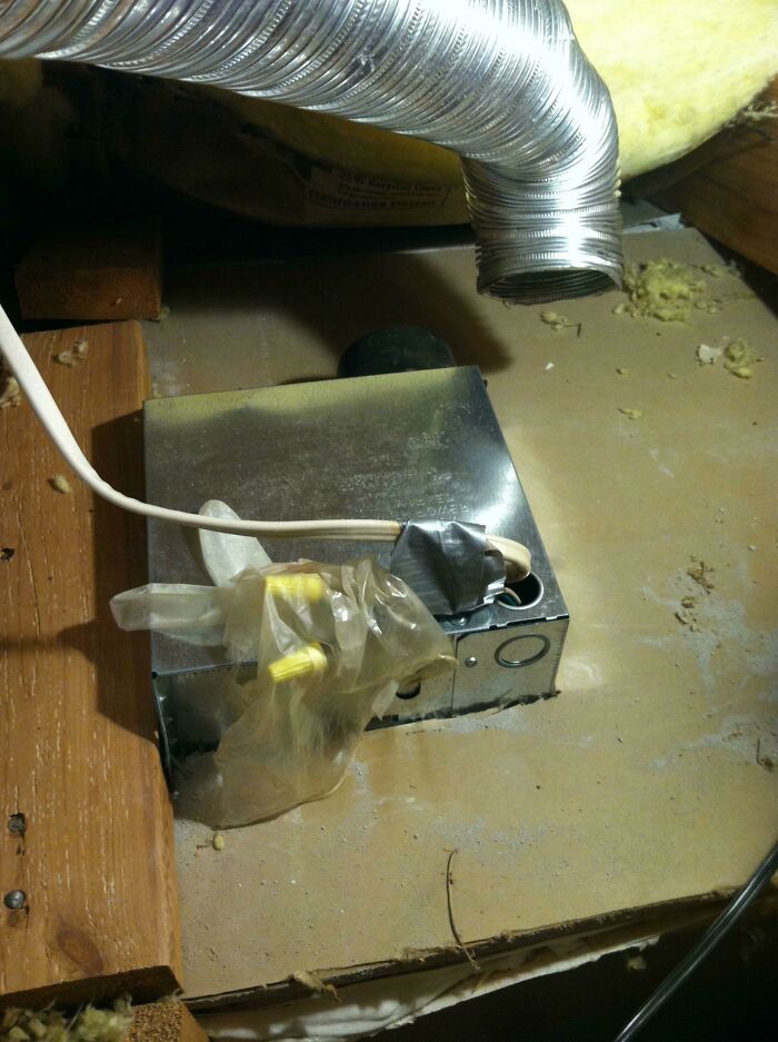 A dangerous DIY fail: exposed electrical wiring and a light fixture in an attic space.