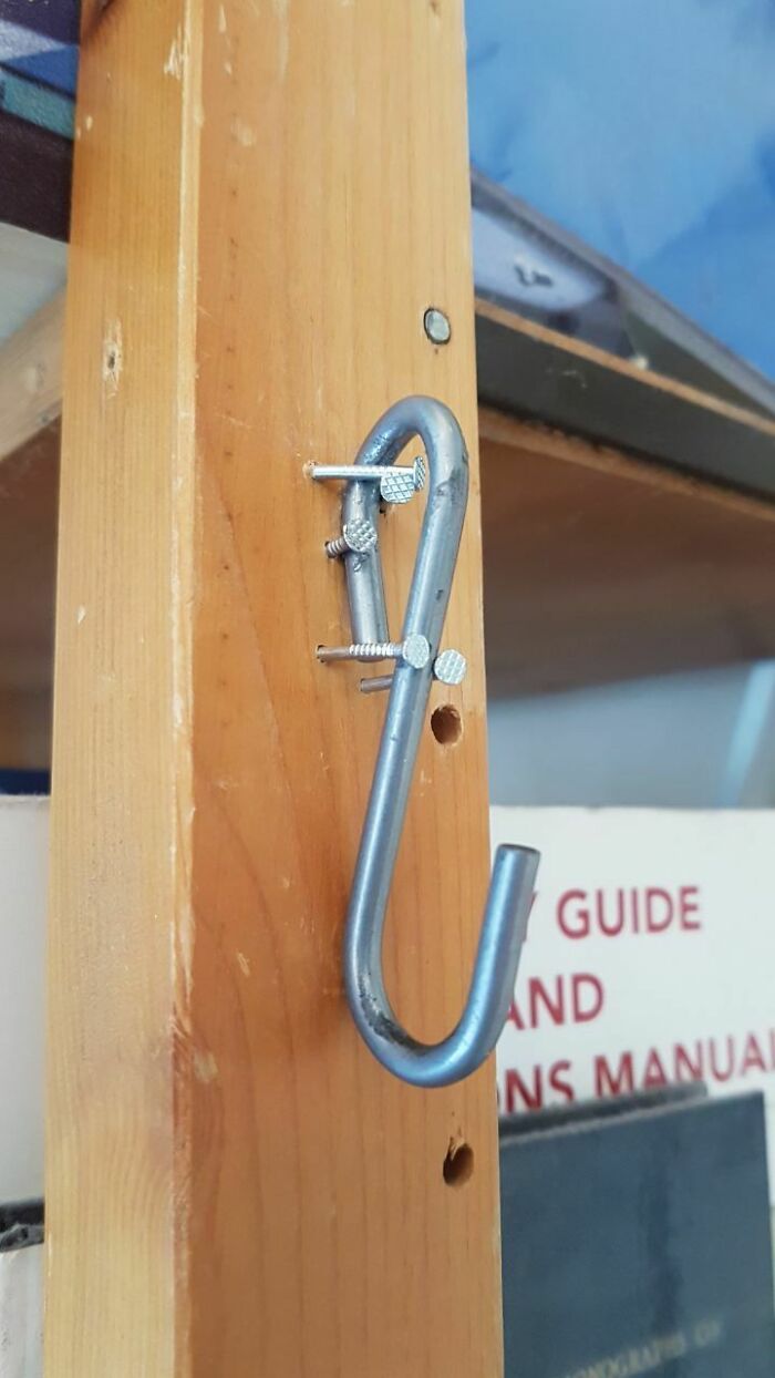A metal S-hook crudely nailed into a wooden post, an obvious DIY fail.