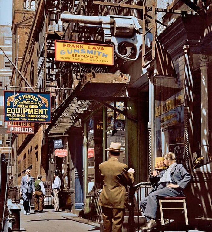 An old historical colorized photo captures a bustling city street with a prominent gunsmith sign, making the past come alive.