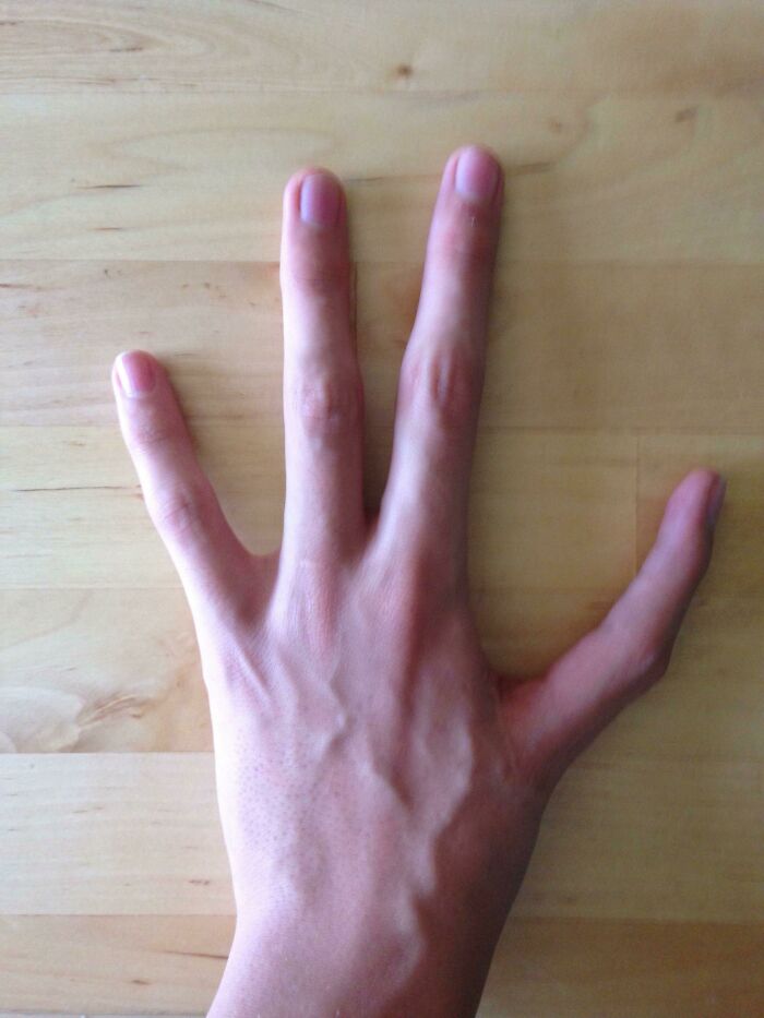 Hand displaying rare six fingers on wooden surface