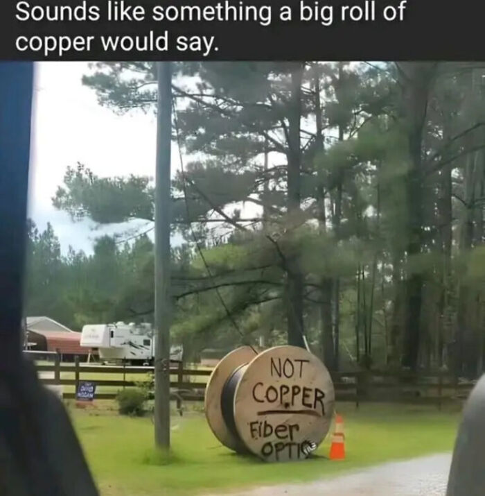 A large wooden spool with "NOT COPPER Fiber Optic" written on it, captured in a funny internet photo.
