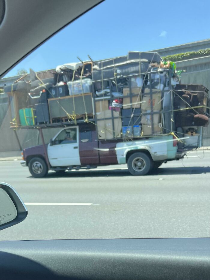 Pickup truck overloaded with household items secured by ropes, a moving fails example.