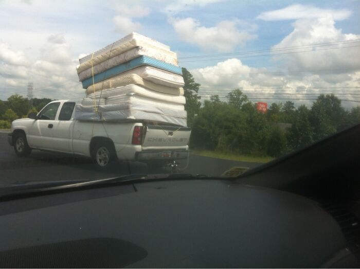 Pickup truck dangerously loaded with multiple mattresses stacked high in moving fails pics