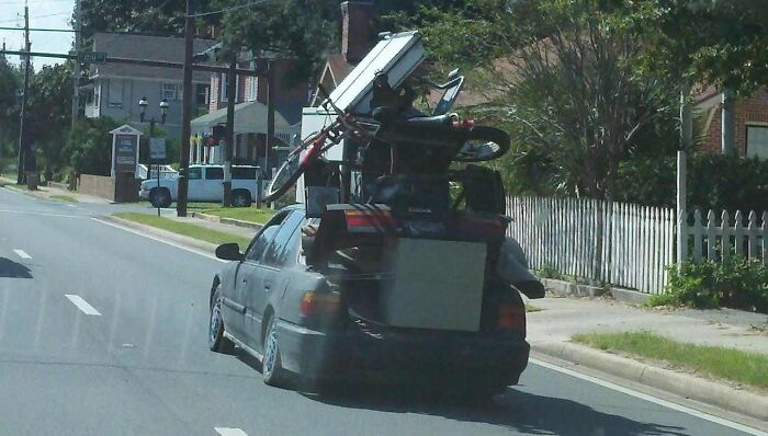Car carrying large furniture and items stacked unsafely for moving fails