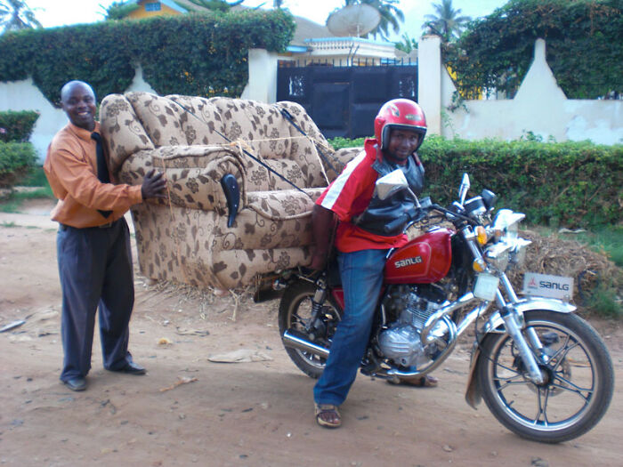 Motorcycle moving fail with a large sofa tied and lifted behind bike