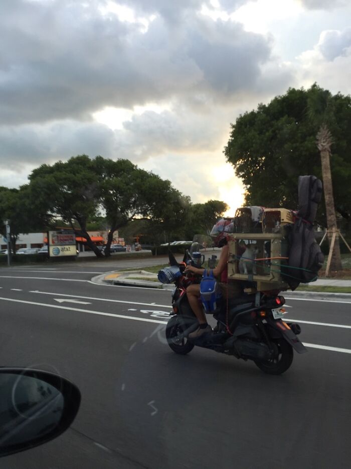 Motorcycle carrying large items stacked high in unusual moving fails situation
